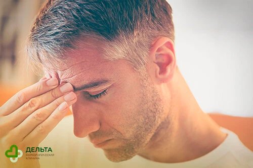 Мужчина потирает пальцами лоб