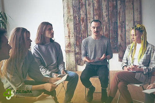 Люди сидят в круге на собрании по двеннадцати шагам